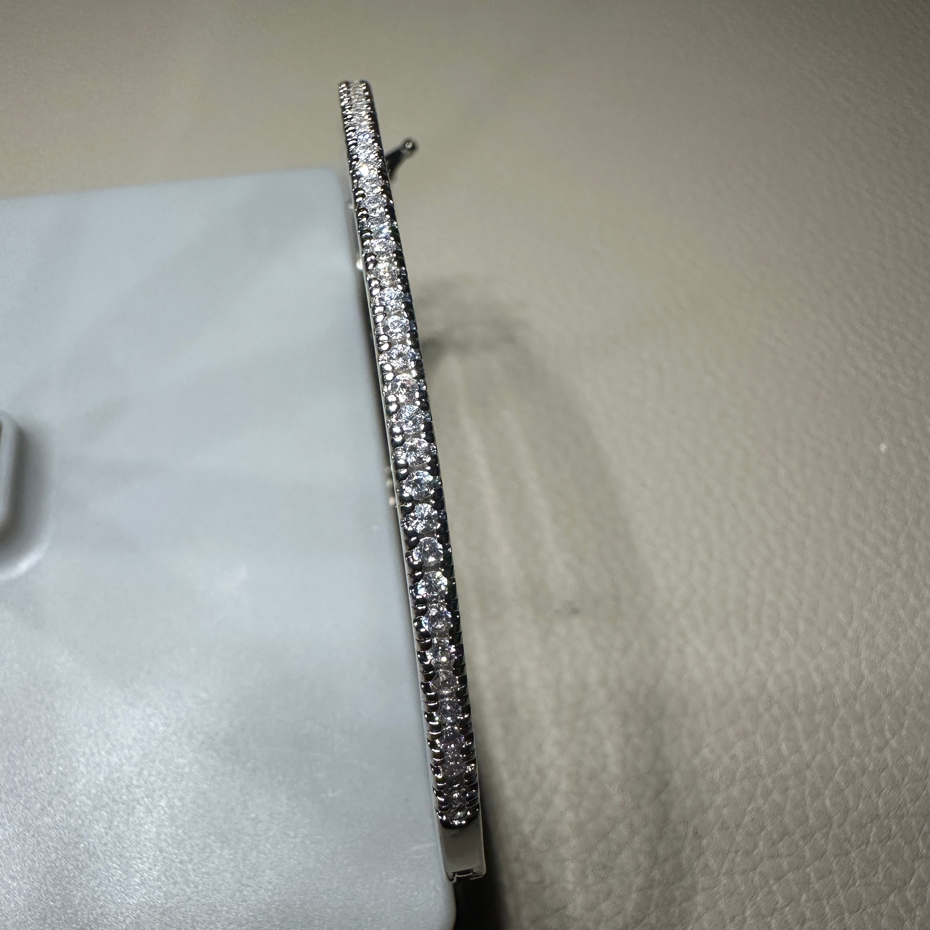 Silver bracelet with clear stones on a textured surface