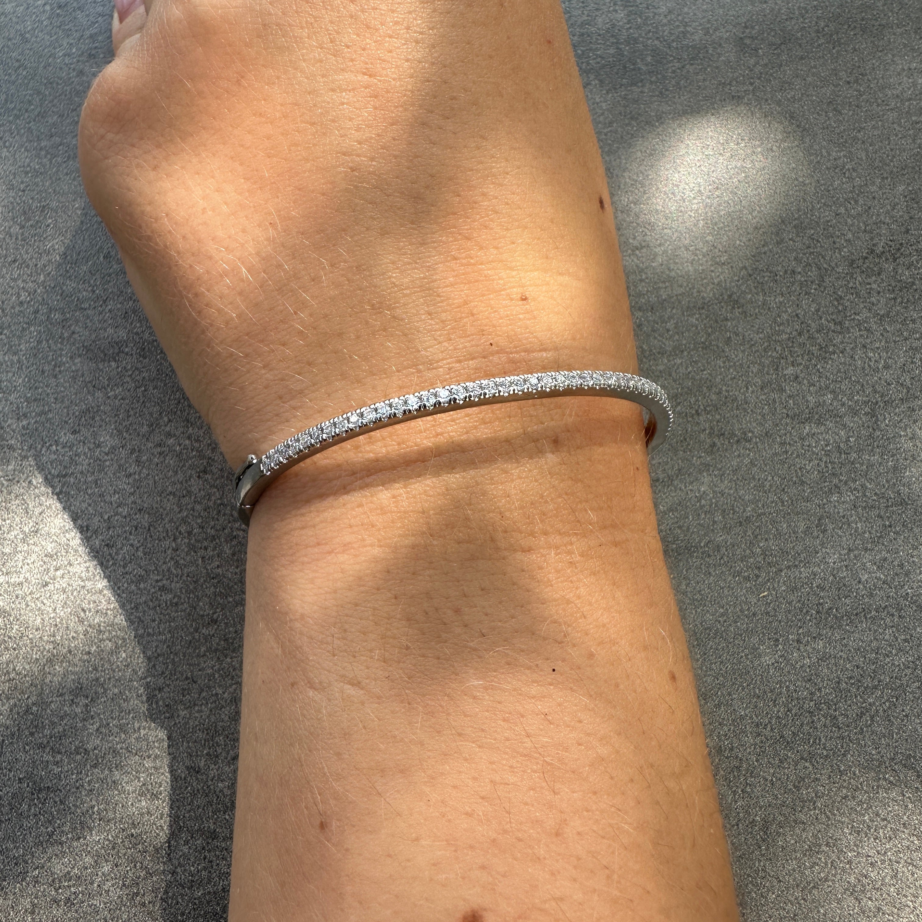 Silver bracelet on a wrist against a gray background
